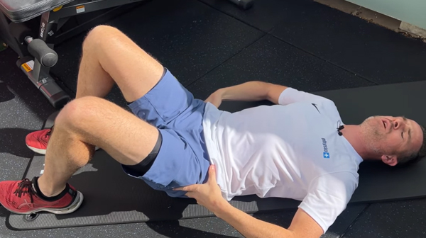 Person performing pelvic tilts on their back – gentle lumbar mobilisation for acute low back pain